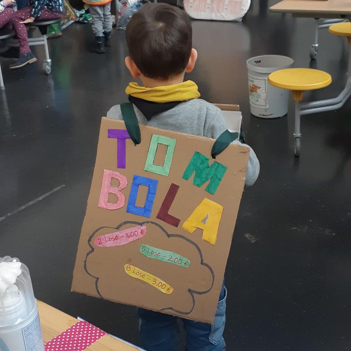 Kind mit Schild auf dem "Tombola" steht.